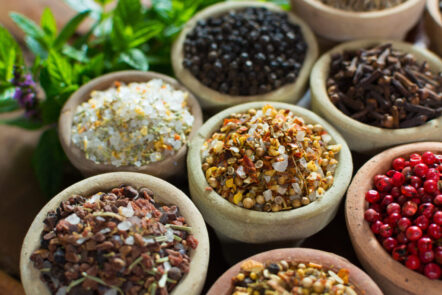 Verschiedene Schalen mit verschiedenen Gewürzen in bunten Farben, die für natürliche Krebsprävention dienen