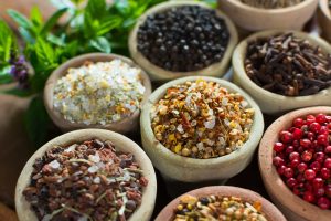 Verschiedene Schalen mit verschiedenen Gewürzen in bunten Farben, die für natürliche Krebsprävention dienen