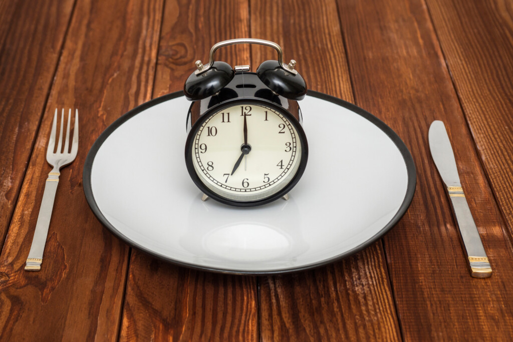 Eine Uhr auf einem weißen Teller steht als Symbol für Wie geht Fasten