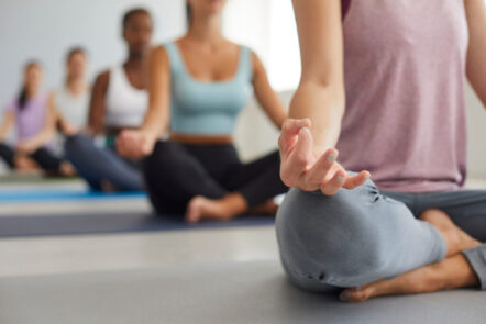 Eine Gruppe von Menschen sitzt in Meditationshaltung in einem hellen Raum, um an Parasympathikus und Sympathikus zu arbeiten