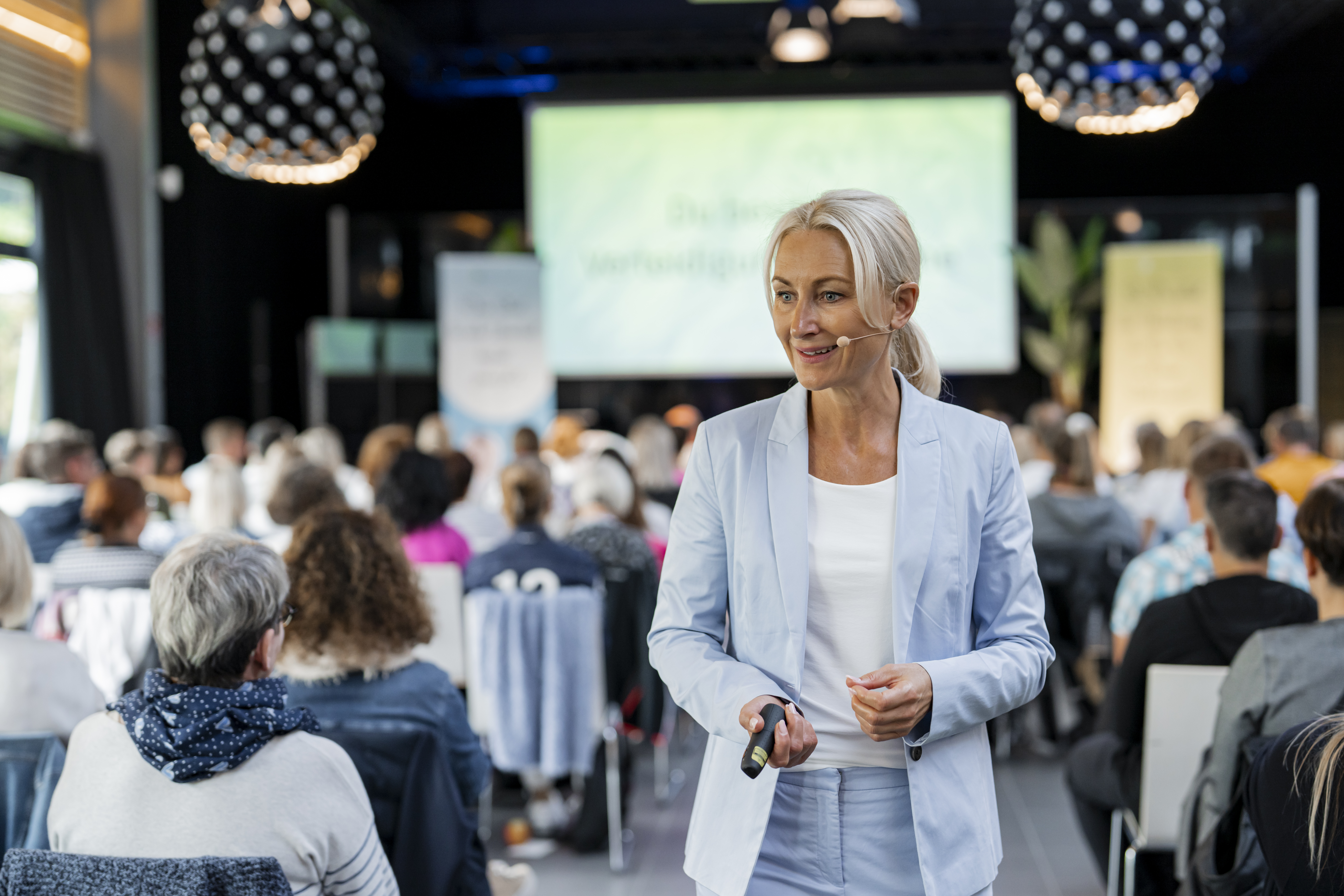 Kerstin Hardt in einem blauen Blazer vor einer Menschenmenge bei ihrem Vortrag zu dem Weg aus Angst und Deppression