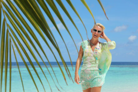Kerstin Hardt vor einem Palmenblatt an einem weißen Sandstrand mit blauem Wasser zeigt wie leicht es ist, endlich wieder glücklich zu sein