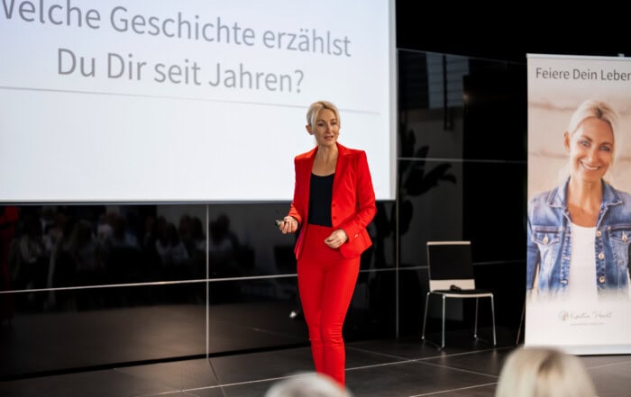 Kerstin Hardt auf der Bühne mit einem roten Blazer Anzug erklärt, wie das unserer Leistungswasser schädlich ist