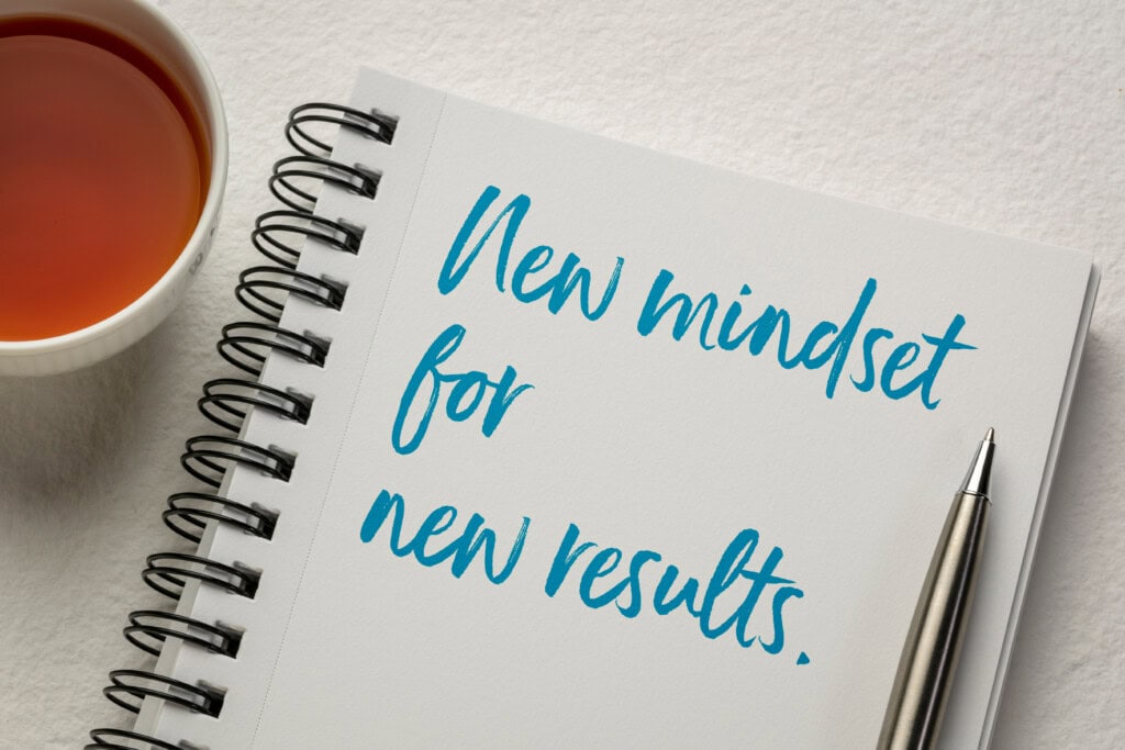 Ein Bild eines weißen Schreibblockes mit blauer Schrift new Mindset new Results steht sinnbildlich für Mindset stärken. 